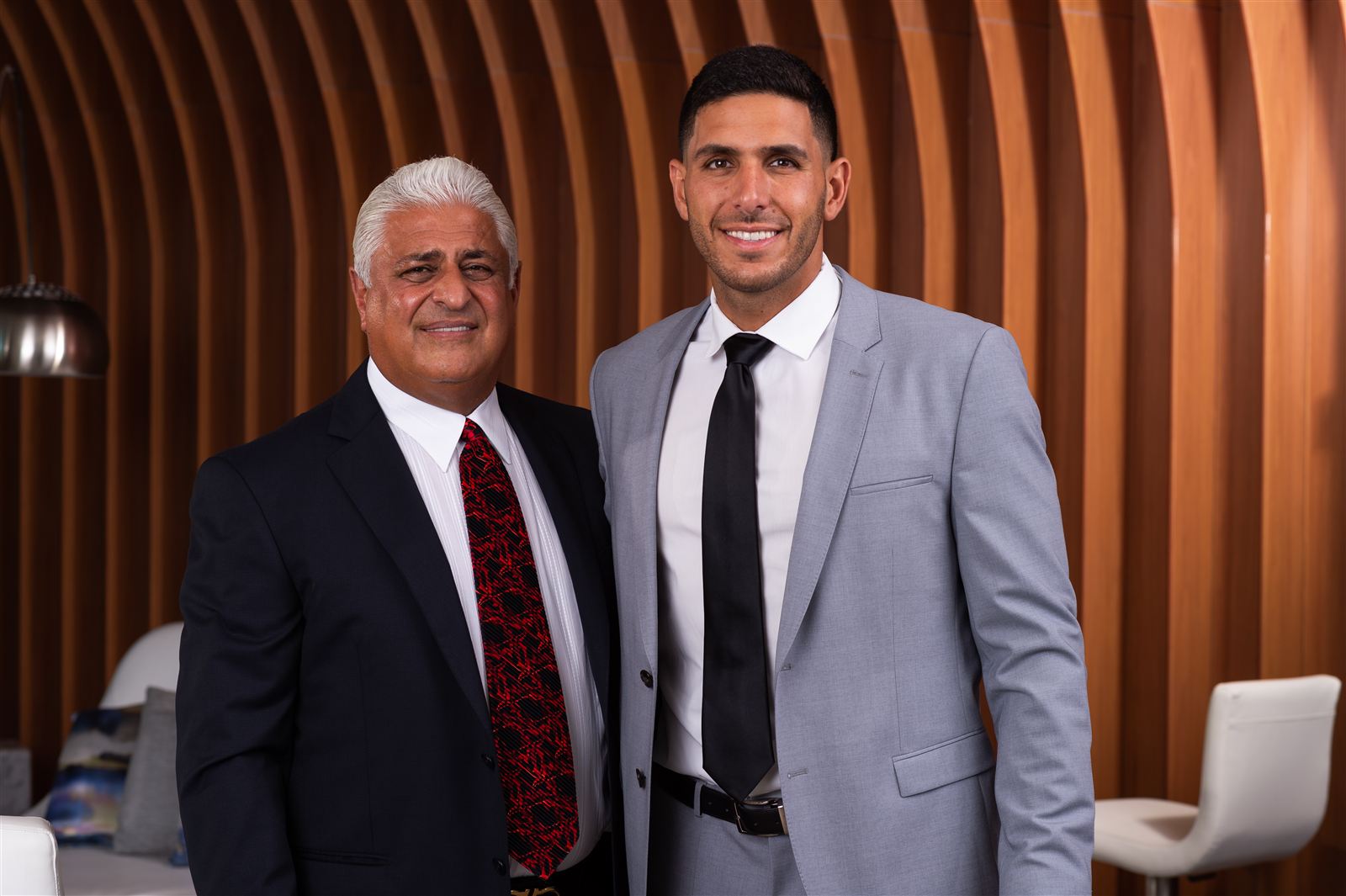Yosi and Guy Gil standing side by side in a wood-paneled room